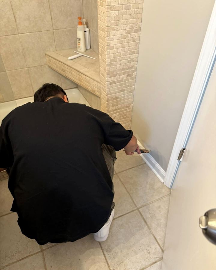 Painter cutting in trim next to a tile floor